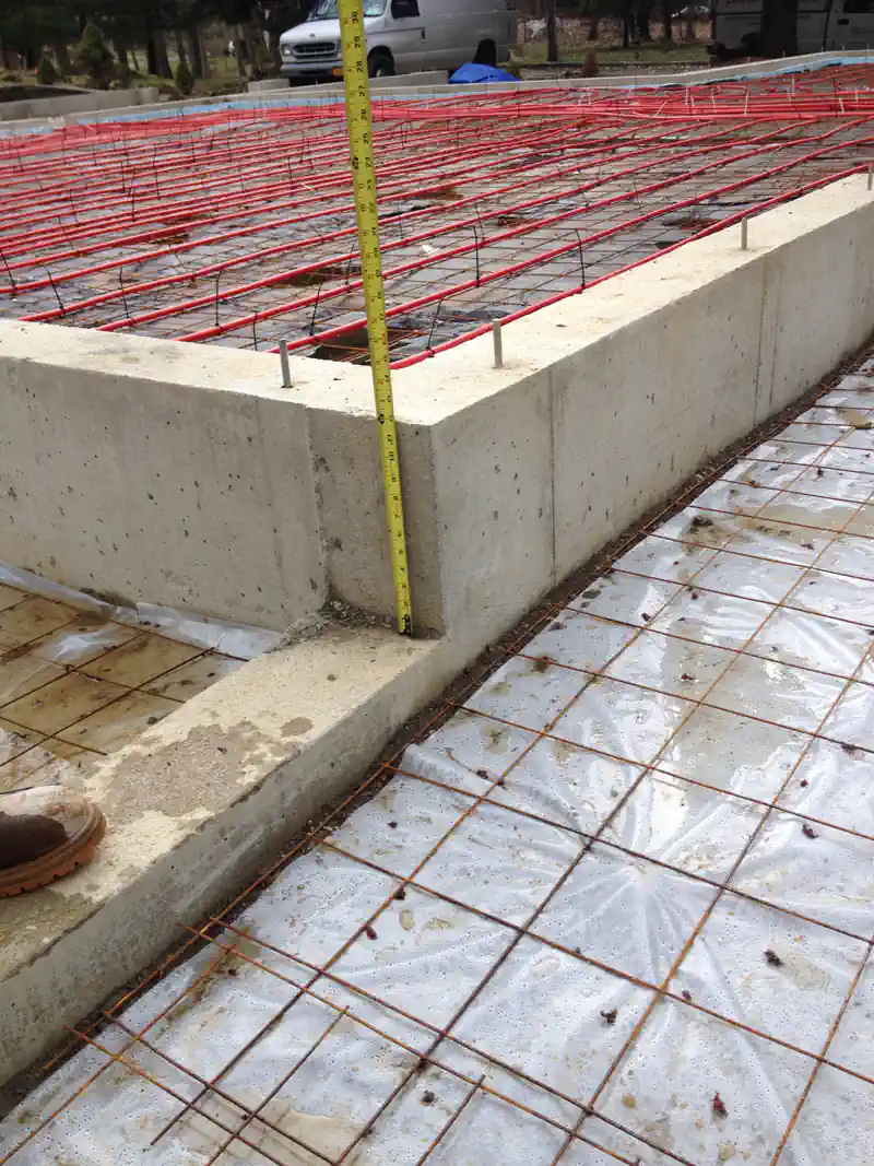 New home construction with radiant heating pipes arranged on a reinforced foundation.