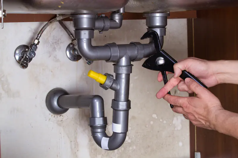 Plumber repairing pipes under sink